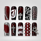 Ten glossy deep wine red and black press-on nails arranged on white, featuring red flames, silver crosses, chains, spikes, rhinestones, white graphics, and a star charm.