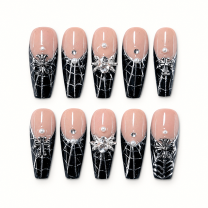 Silver Widow press-on nail set with nude-pink and black web-patterned nails, silver floral charms, pearls, and clear accents.