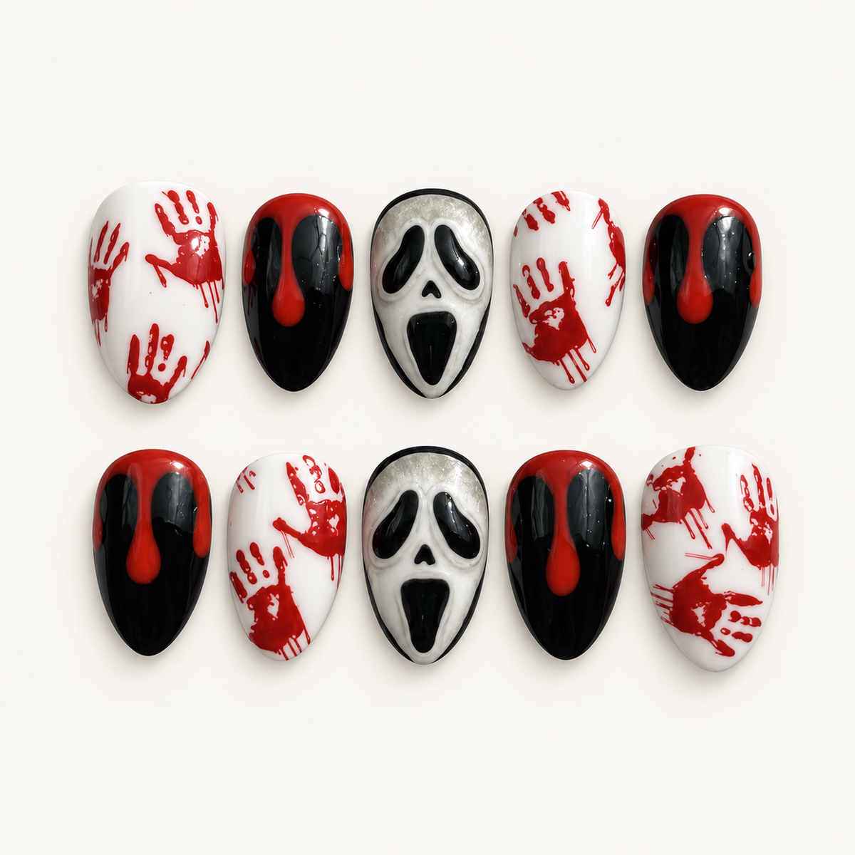 Ten coordinated glossy press-on nails with black, white, crimson drip, handprint, and eerie mask-face designs arranged on a light neutral surface.