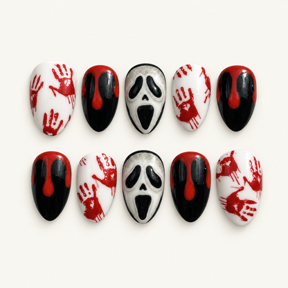 Ten coordinated glossy press-on nails with black, white, crimson drip, handprint, and eerie mask-face designs arranged on a light neutral surface.