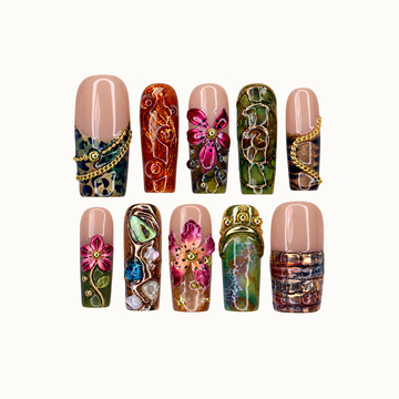 Ten coordinated nails arranged in two rows on a light background, featuring nude sections, magenta flowers, olive mosaics, amber swirls, and gold-tone accents.