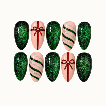 Ten nails arranged in two rows on a light neutral background, featuring emerald glitter, blush pink bases, red gift bows, and green and silver curved stripes.