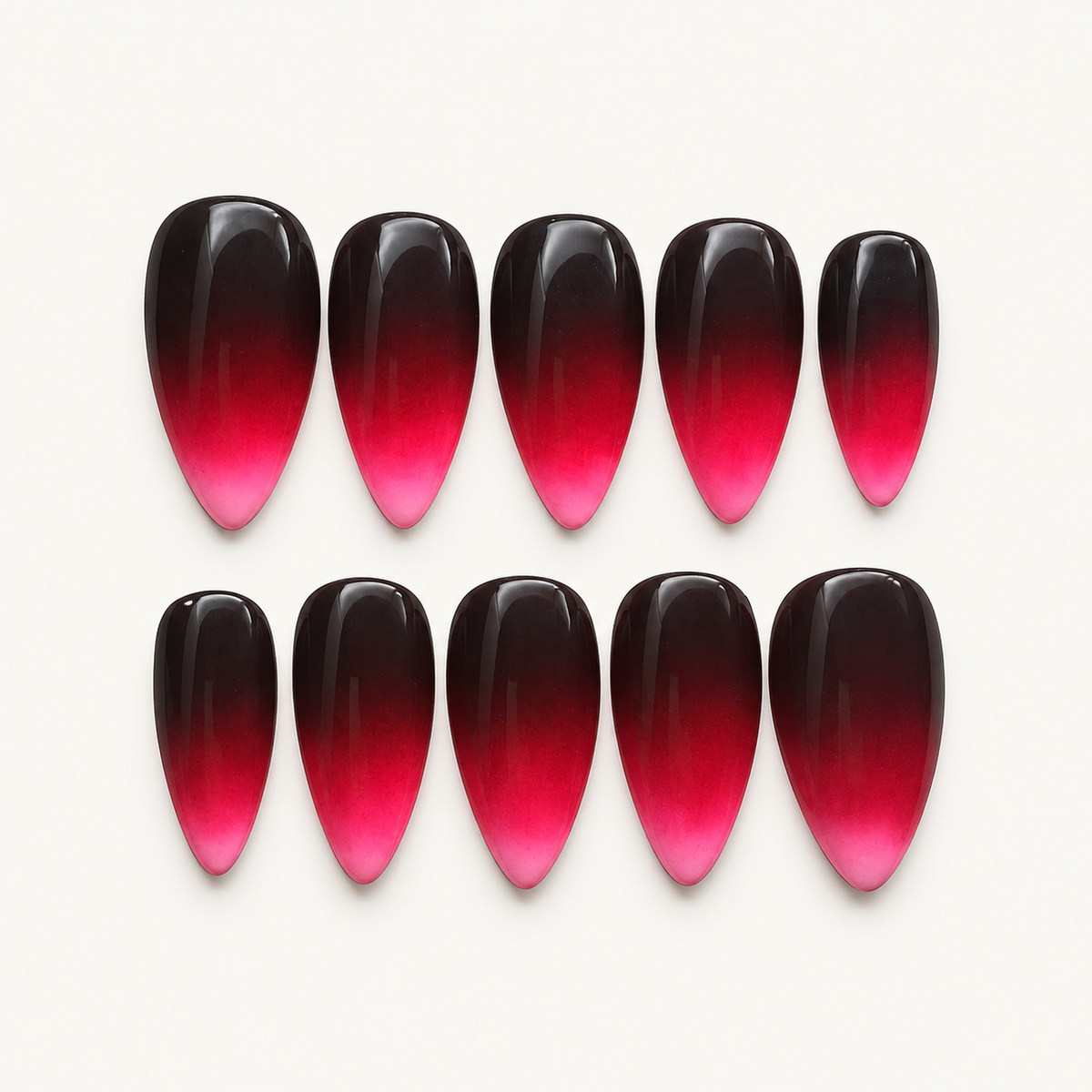 Glossy black-plum to fuchsia-pink ombré press-on nails displayed as a coordinated set.