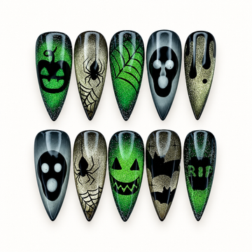 Ten long pointed press-on nails arranged on a light background, featuring green and gold glitter, black webs, spiders, and spooky face motifs.