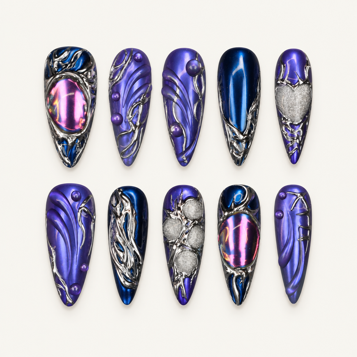 Ten coordinated dark blue and violet press-on nails with chrome silver raised swirls, droplets, and reflective pink accents on a black textured surface.