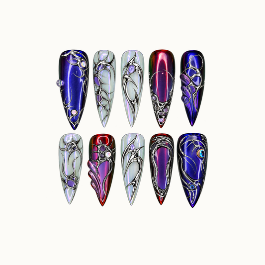 Ten pointed nails arranged in two rows on a light background, featuring cobalt, wine-purple, and pearly iridescent bases with silver-tone ornamental details.