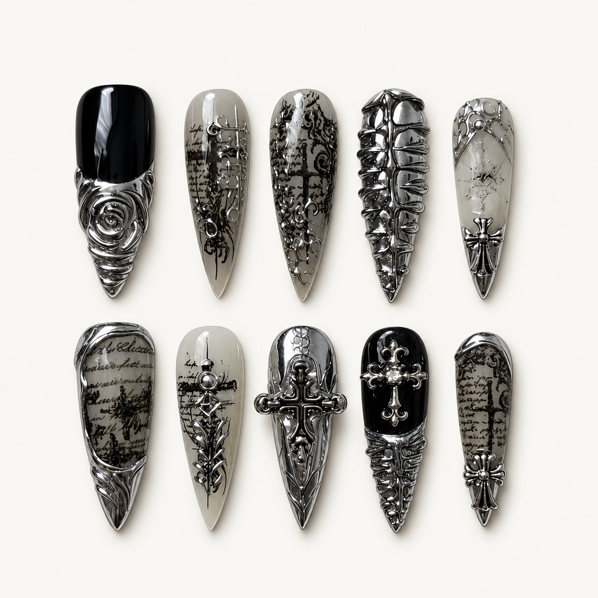 Ten coordinated gothic press-on nails displayed on a textured gray surface, with black, smoky gray, and silver chrome-look cross and rose details.