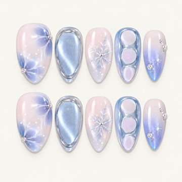 Ten pink and icy blue nails in two rows on a light greige background, with snowflakes, pearl accents, shimmer, and raised reflective details.