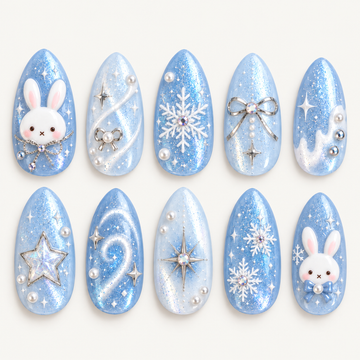 Ten blue pointed nails arranged in two rows on a light neutral background, featuring white bunnies, snowflakes, silver-toned bows, stars, and pearly accents.