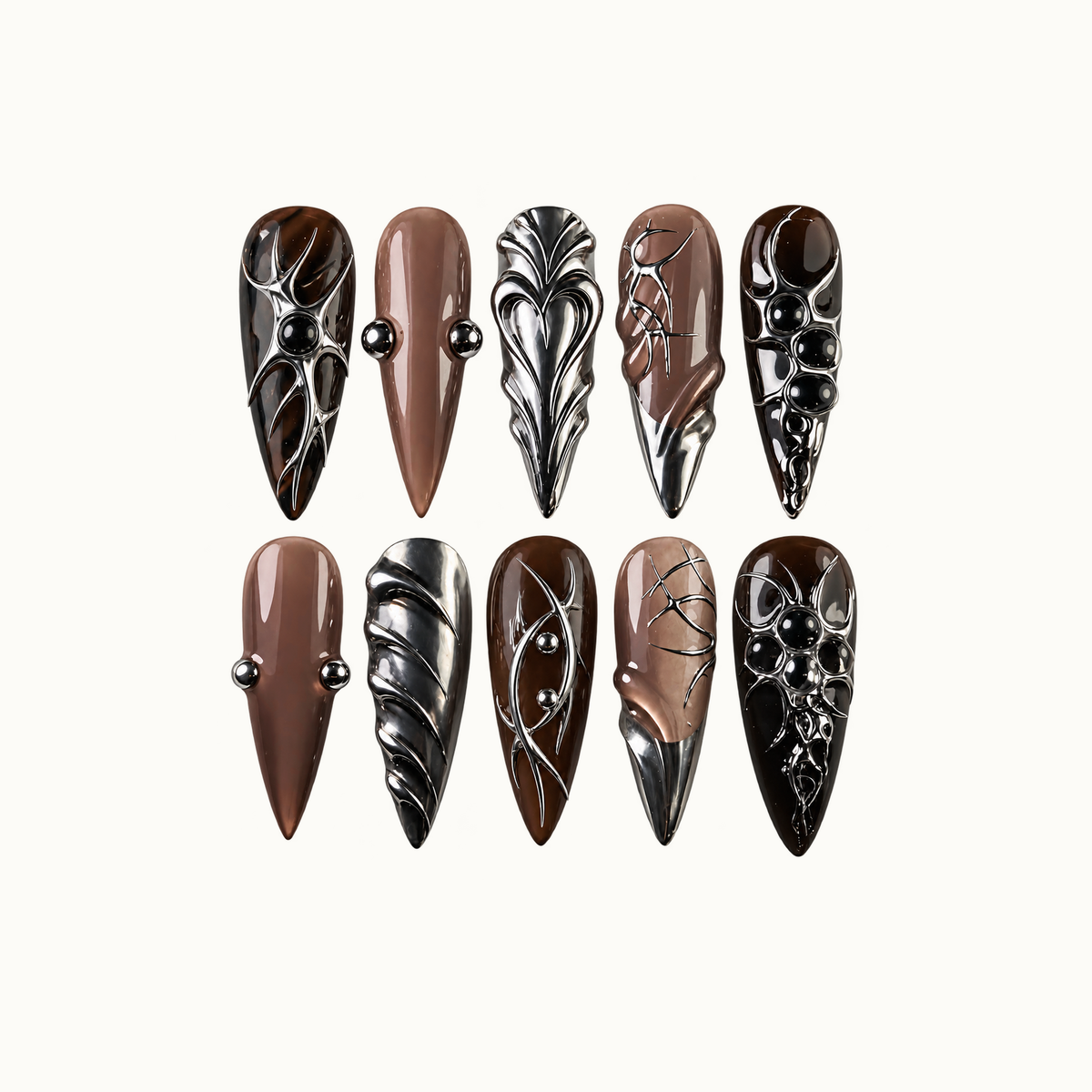 Ten pointed nails arranged in two rows on a light background, with mocha and taupe bases, sculptural silver accents, and black rounded embellishments.
