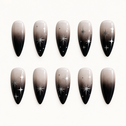 Ten pointed press-on nails with a greige-to-black ombré fade and silver celestial starburst accents on select nails.