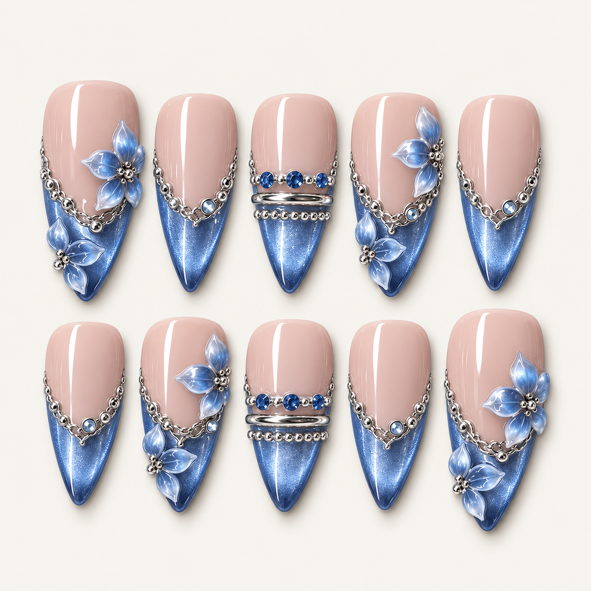 Ten blush pink and shimmering blue nails arranged in two rows, with blue petal accents, silver-toned chains, and blue gems.