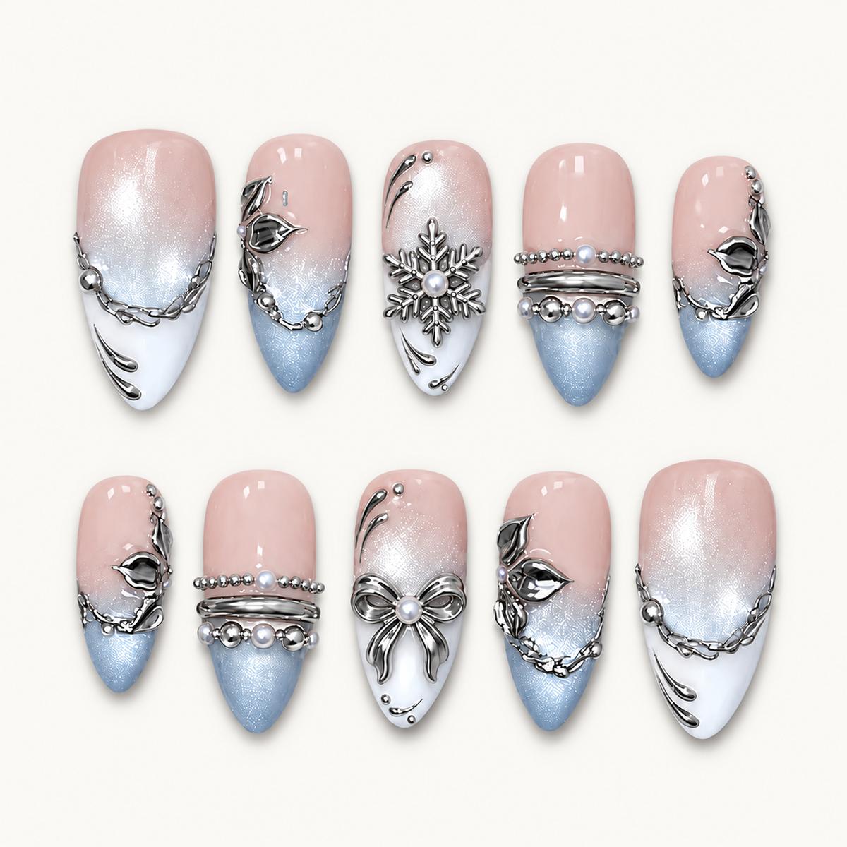 Ten Blush Snowfall nails arranged in two rows on a pale neutral background, showing blush-to-blue color, white tips, and silver-tone winter details.