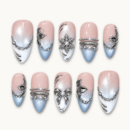 Ten Blush Snowfall nails arranged in two rows on a pale neutral background, showing blush-to-blue color, white tips, and silver-tone winter details.