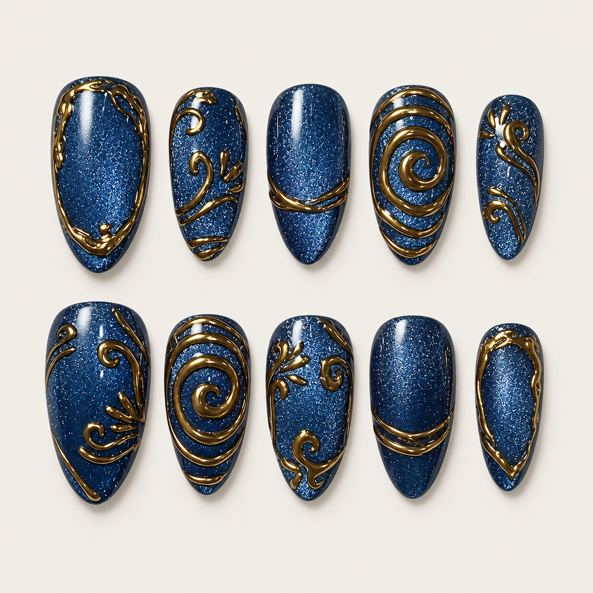 Ten deep blue shimmer press-on nails arranged in two rows on a light background, with varied gold spirals, scrolls, bands, and borders.