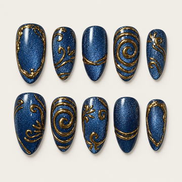 Ten deep blue shimmer press-on nails arranged in two rows on a light background, with varied gold spirals, scrolls, bands, and borders.