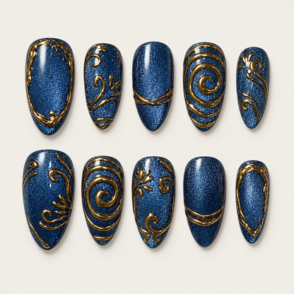 Ten deep blue shimmer press-on nails arranged in two rows on a light background, with varied gold spirals, scrolls, bands, and borders.