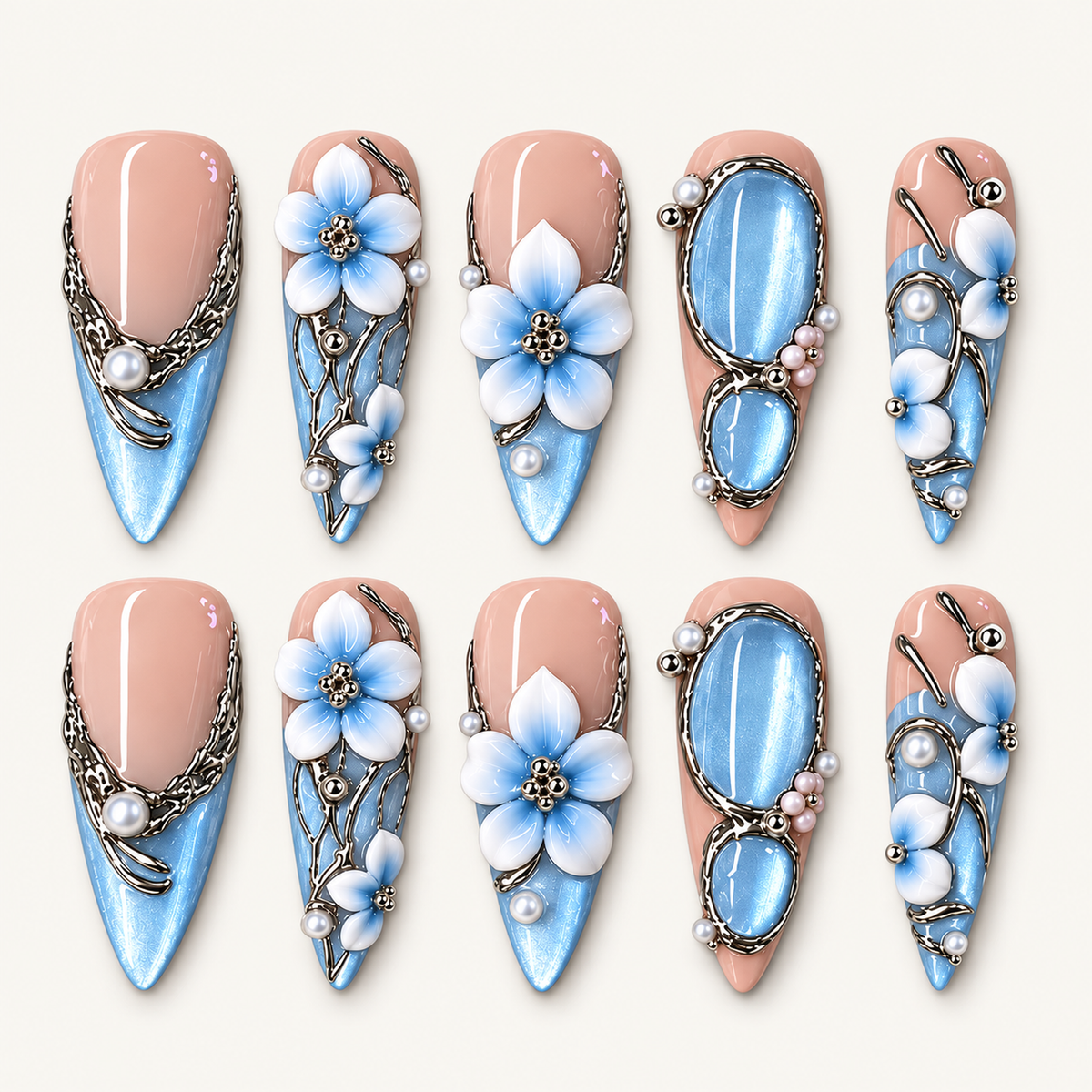 Ten blush pink and shimmering blue press-on nails arranged in two rows, with blue-and-white flowers, oval blue accents, silver-toned flourishes, and pearl-like beads.