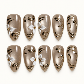 Ten glossy taupe-greige nails arranged in two rows on a light background, featuring white floral accents, gold-tone swirls, and small decorative dots.