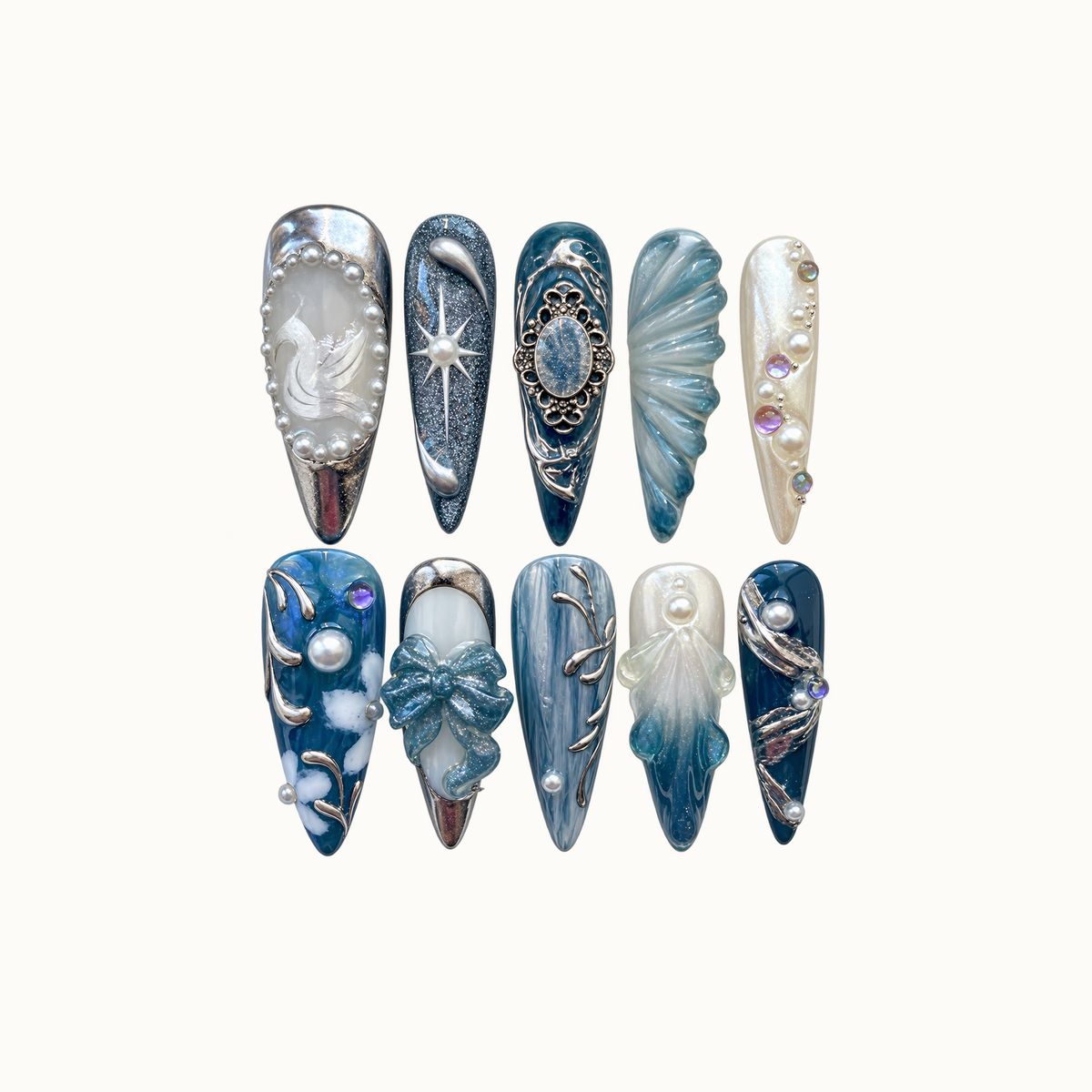 Ten blue, teal, and pearl white nails arranged in two rows on a light background, with swan, starburst, bow, shell-like, and silver ornamental details.