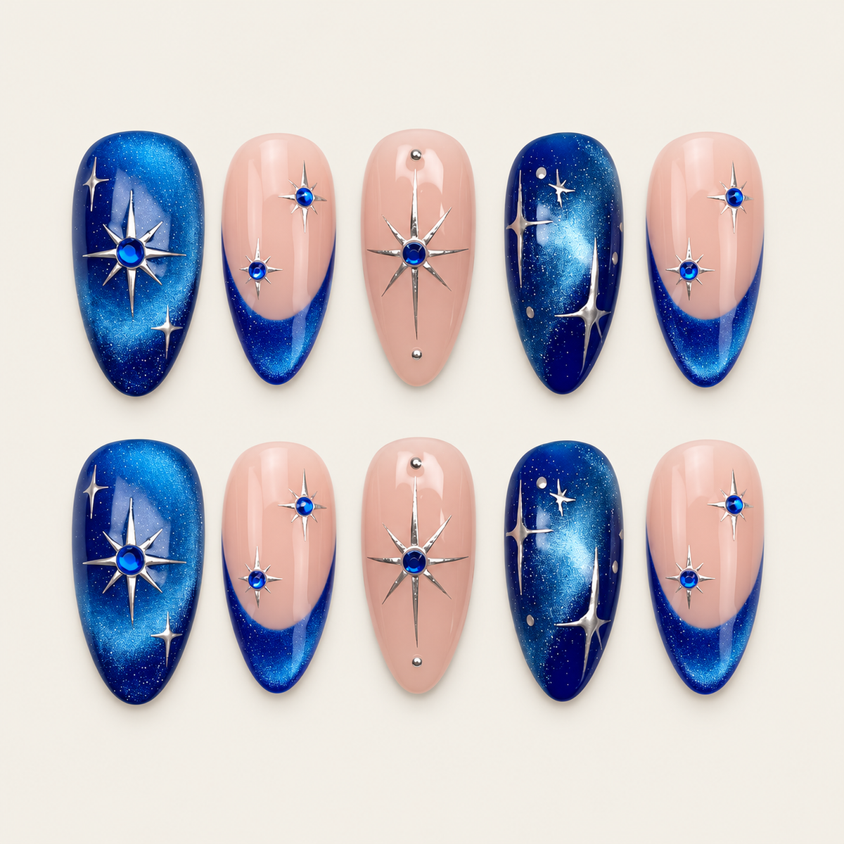 Ten blush pink and shimmering blue nails arranged in two rows on a greige background, with silver starbursts, blue gem-like accents, and blue French tips.