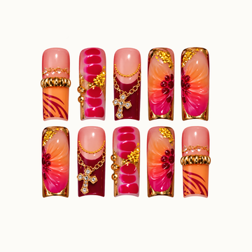 Ten coordinated nails arranged in two rows on a light neutral background, featuring peach and fuchsia flowers, burgundy accents, gold-tone chains, and cross charms.