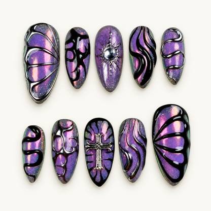 Ten coordinated purple mirror-shimmer press-on nails with black abstract swirls, silver-toned raised accents, cross detail, and pink-green flashes.
