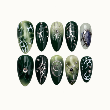 Ten glossy green nails arranged in two rows on a light neutral background, featuring silver-tone celestial lines, white curves, and a blue oval accent.