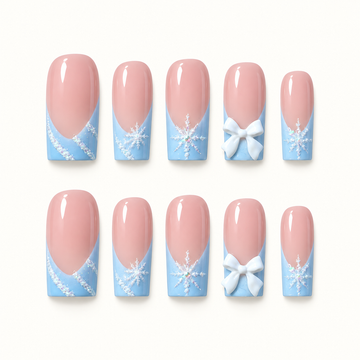Ten glossy pink and icy blue press-on nails arranged in two rows, with white snowflakes, shimmering details, and raised bow accents.