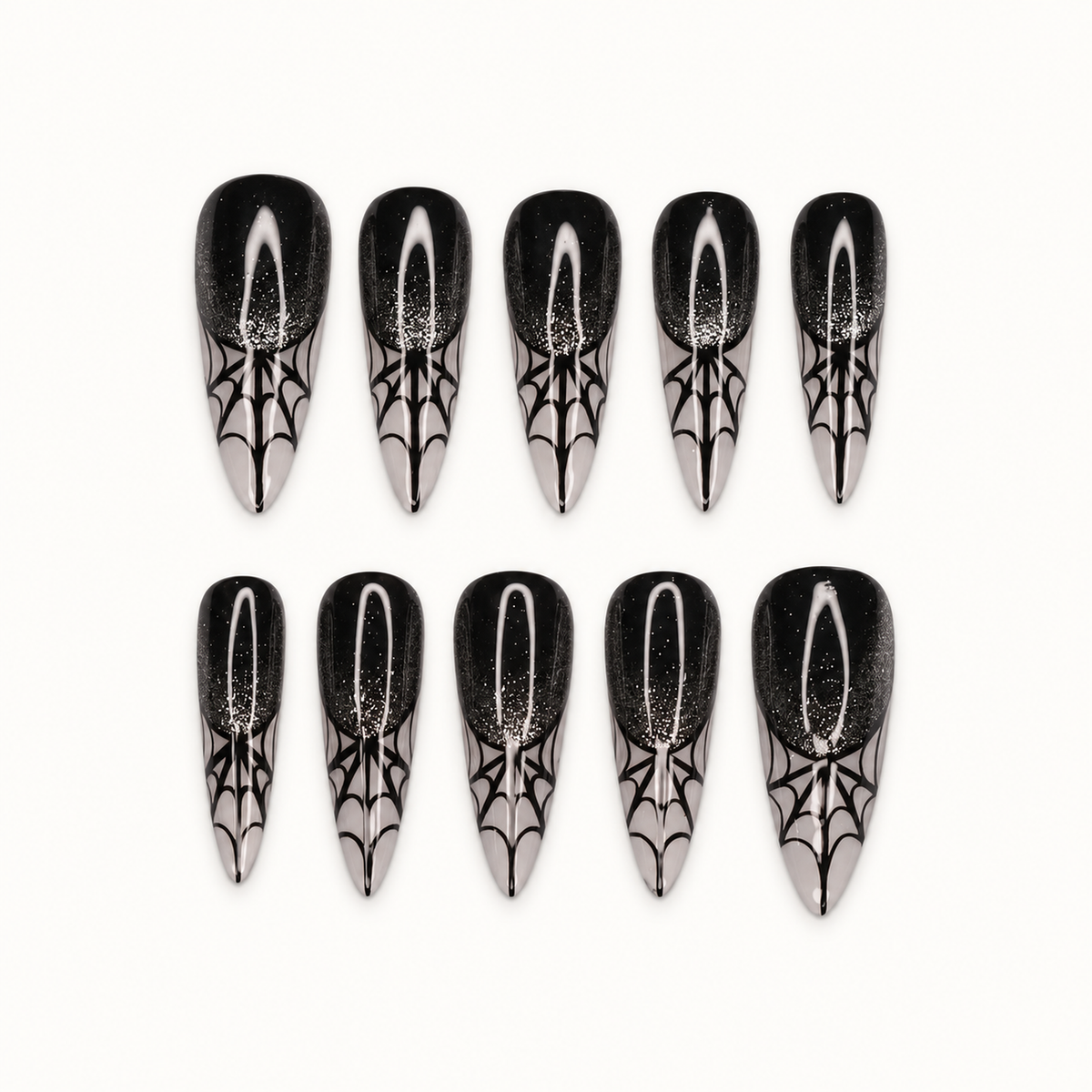 Ten black and silver press-on nails arranged on a light background, featuring pointed smoky tips with spiderweb-inspired linework.