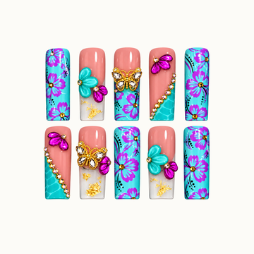 Ten coordinated nails in two rows on an off-white background, featuring turquoise and purple florals, coral pink accents, raised petals, and jeweled butterflies.