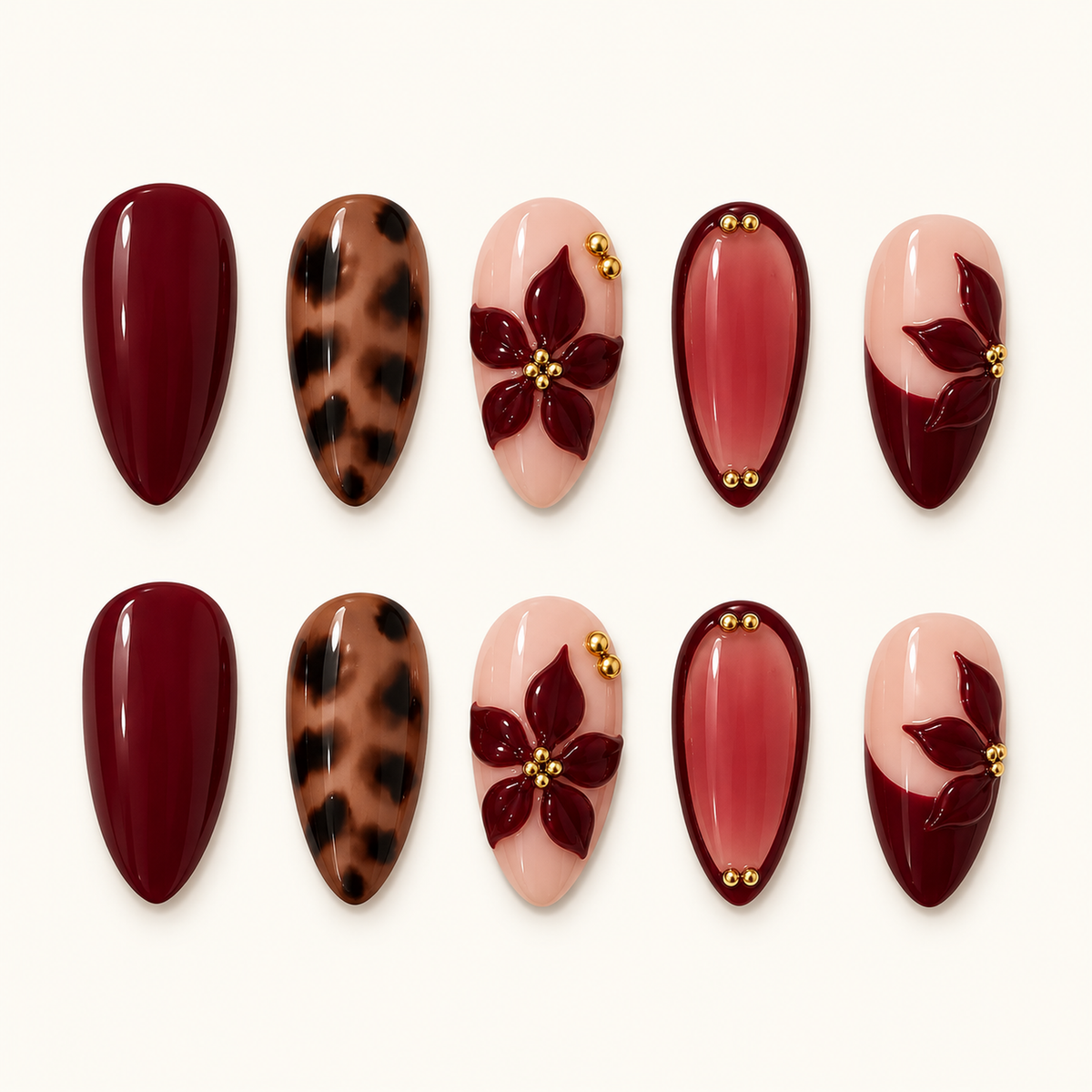 Ten glossy nails arranged in two rows on a light neutral background, featuring burgundy solids, leopard spots, blush floral accents, and gold-tone beads.