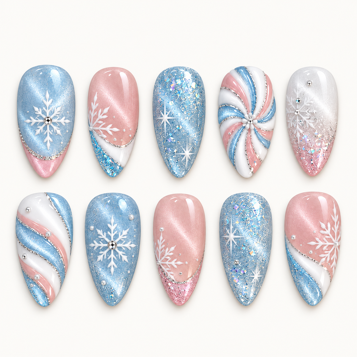 Ten pastel blue, pink, and white nails arranged in two rows on a light background, featuring snowflakes, starbursts, glitter, and swirls.