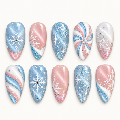 Ten pastel blue, pink, and white nails arranged in two rows on a light background, featuring snowflakes, starbursts, glitter, and swirls.