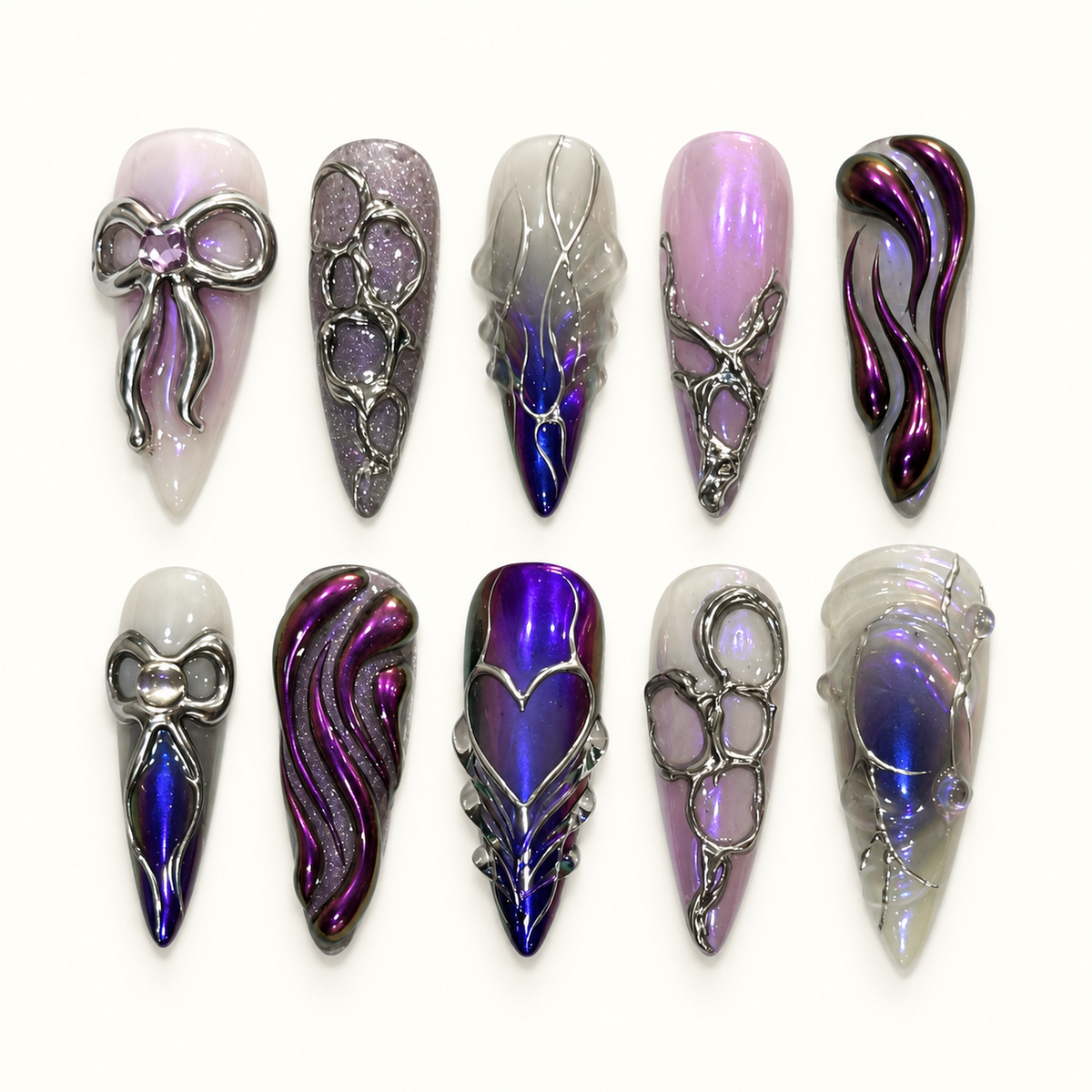 Ten pointed press-on nails arranged on a light textured background, featuring purple chrome, pale lilac, raised silver-toned bows, hearts, pebble frames, and flowing swirls.