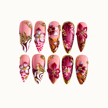 Ten coordinated nails in two rows on a light background, featuring pink and burgundy flowers, animal-print accents, gold-tone butterflies, and gems.