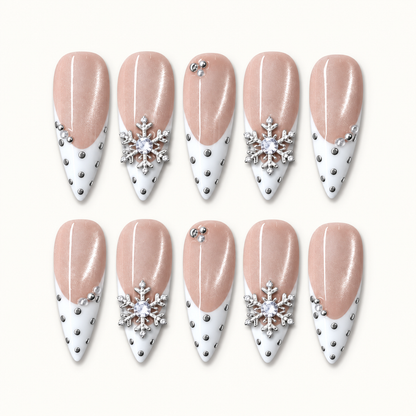 Ten Pearl Snowfall nails arranged in two rows on a light background, showing blush shimmer, white pointed tips, silver-tone dots, and snowflake accents.