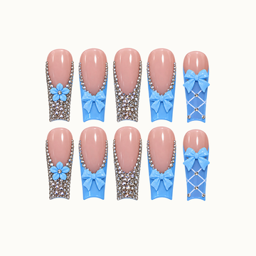 Ten blush-pink and sky-blue nails arranged in two rows on a light neutral background, with blue bows, flowers, rhinestones, and white lattice accents.