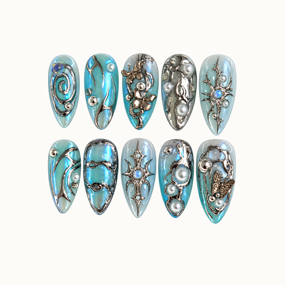 Ten icy blue and aqua nails in two rows on a light neutral background, decorated with silver-tone swirls, butterflies, starbursts, and pearl-like accents.