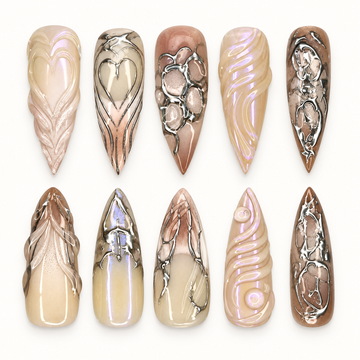 Chrome Relic press-on nail set arranged in a clear case, showing taupe, cream, and brown nails with silver-toned ornate accents.