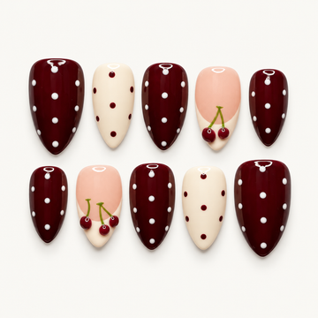 Ten glossy nails arranged in two rows on a light background, featuring burgundy and ivory polka dots with blush pink cherry accents.