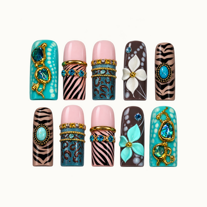Ten decorated nails arranged in two rows on a light background, featuring turquoise accents, pink and black stripes, teal spots, raised flowers, and gold-tone details.