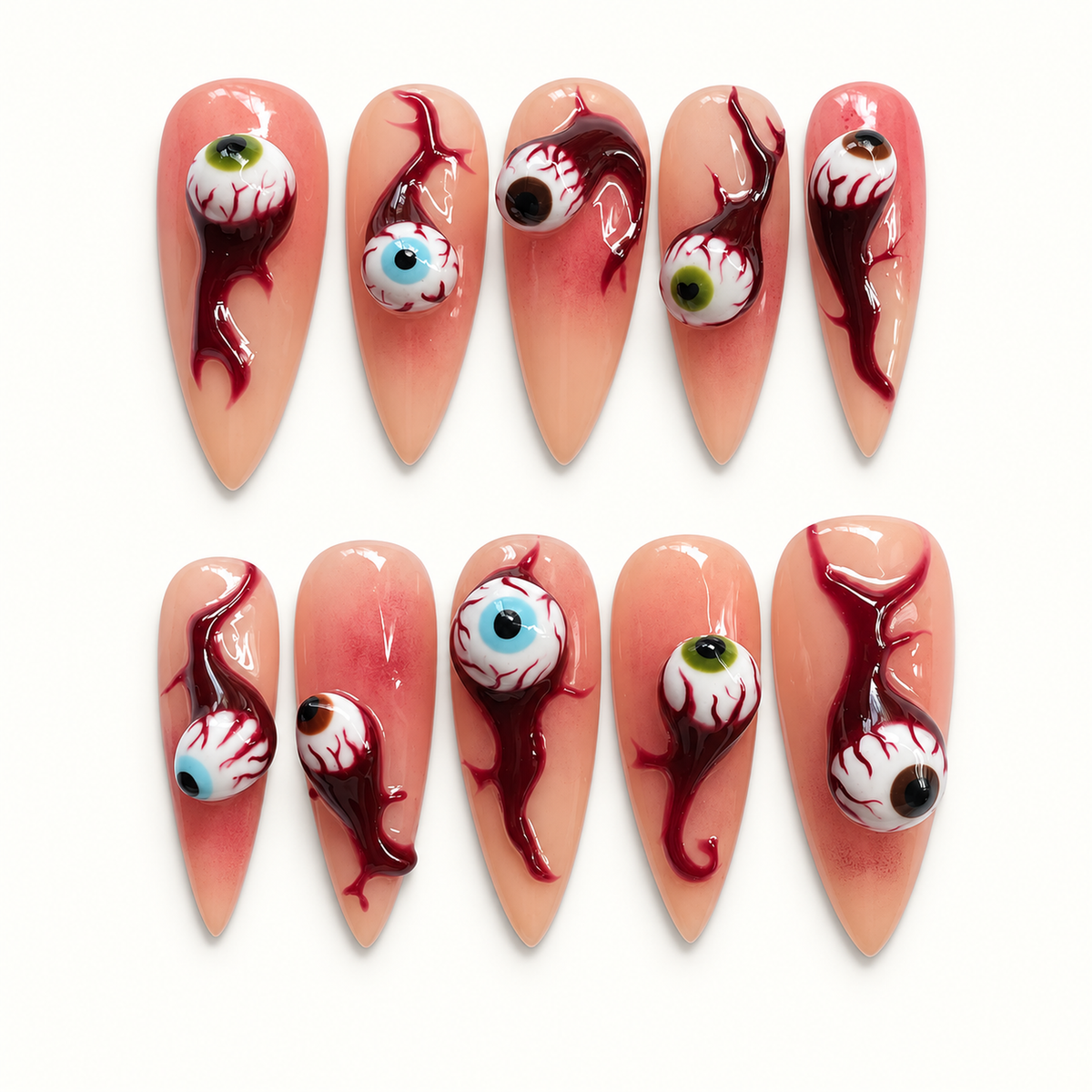 Ten glossy nude-peach press-on nails arranged on a pale background, featuring raised bloodshot eyeballs and deep burgundy drip artwork.