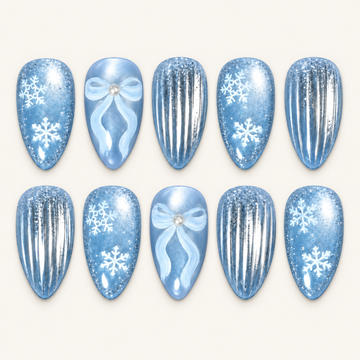 Ten icy blue nails arranged in two rows on a light greige background, with white snowflakes, pale blue bows, and reflective silver stripes.