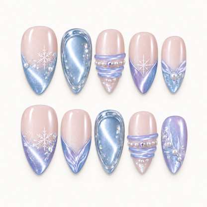 Ten nails arranged in two rows on a light neutral background, showing blush-pink bases, blue and lilac shimmer, snowflakes, and pearl-like accents.
