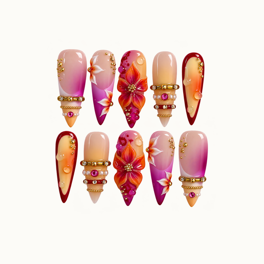 Ten coordinated nails arranged in two rows on a light background, featuring pink-orange gradients, raised flowers, burgundy borders, and gold-tone embellishments.