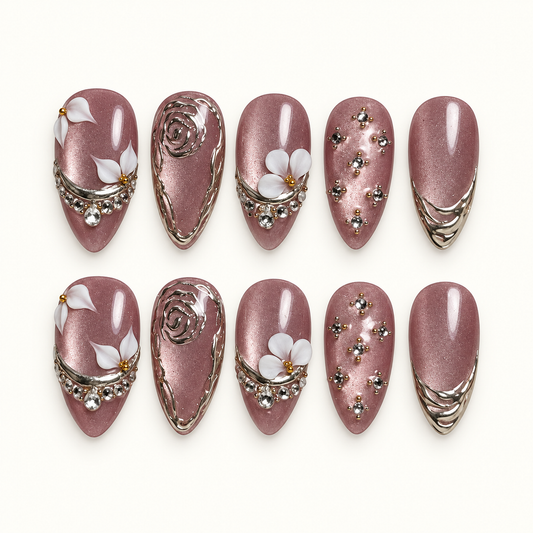 Ten mauve shimmer nails arranged in two rows on a light background, with white flowers, silver-toned rose outlines, curved tip bands, and clear gems.