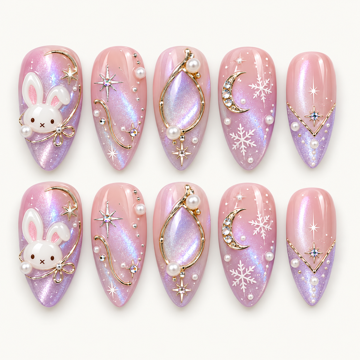 Ten pink and lilac shimmer nails arranged in two rows, featuring white bunnies, gold-toned lines, crescent moons, stars, snowflakes, and pearl-like accents.