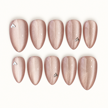 Ten blush-nude shimmer nails arranged in two rows on a light neutral background, with glossy reflections and four silver-toned heart accents.