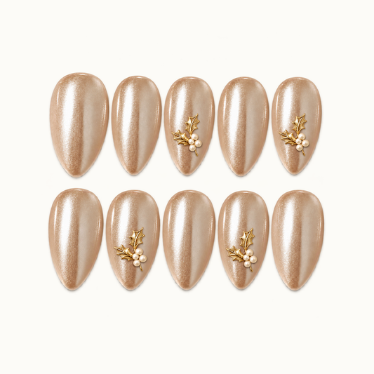 Ten champagne shimmer nails arranged in two rows on a light neutral background, with gold-tone holly leaves and ivory pearl-like clusters on four accent nails.